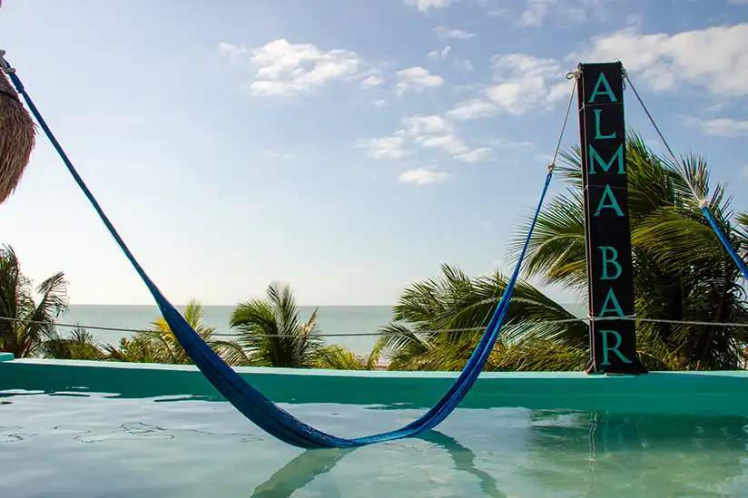 A blue hammock hanging from a rope at the Alma Bar in Holbox during sunset.
