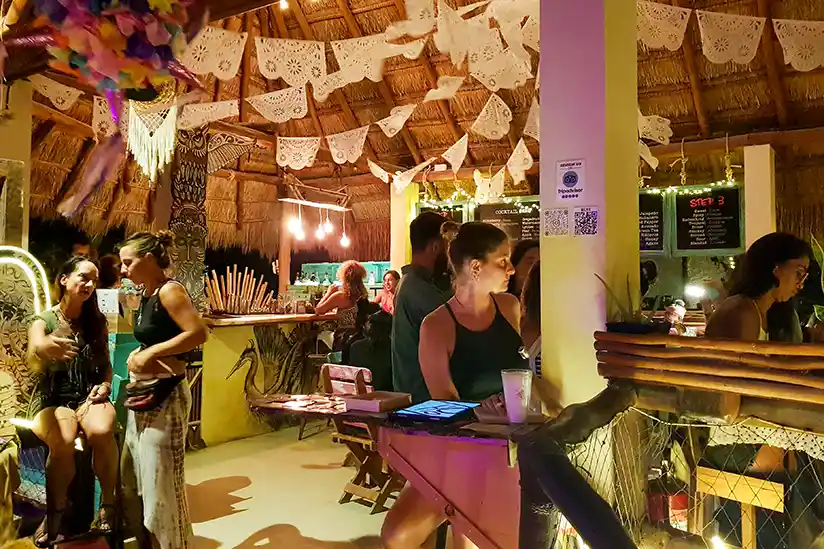 Guests sit at the bar in the Tribu Bar in Holbox and enjoy their drinks in a convivial atmosphere.