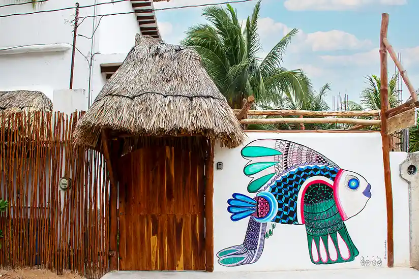 Der Eingang der Casa Sofia Holbox mit einer bunten Wandmalerei am Zaun.