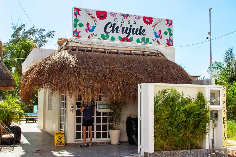 White building at the entrance to the Holbox Hotel Casa Chujuk by Spirit Group with pool.