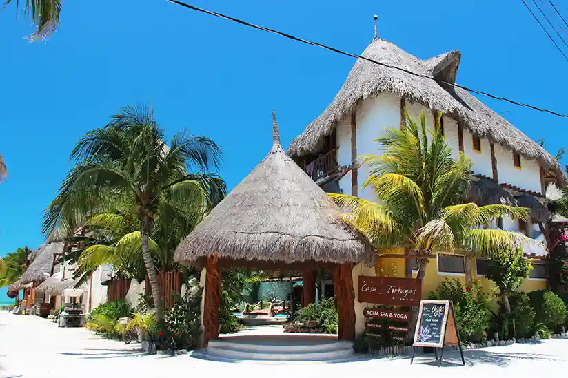 The thatched-roof entrance to the Holbox Hotel Casa Las Tortugas with the pool in the background.