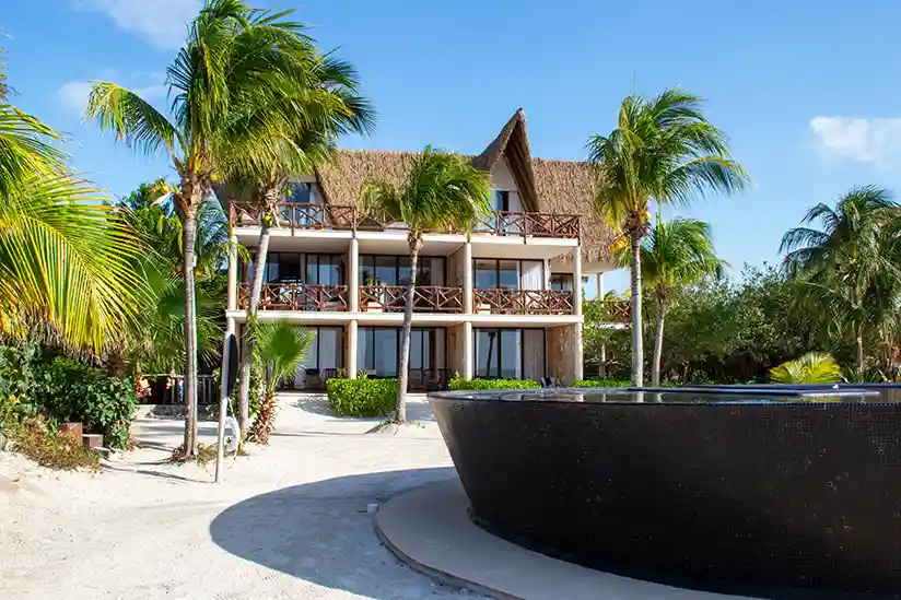 A bungalow at the Holbox luxury hotel Villas Flamingos with a black pool in the foreground.