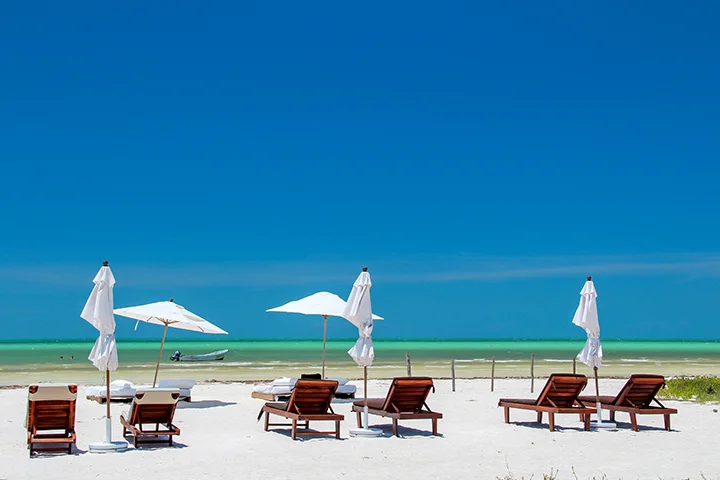 A beach with sun loungers and parasols, ideal for relaxation in the best Holbox hotels.