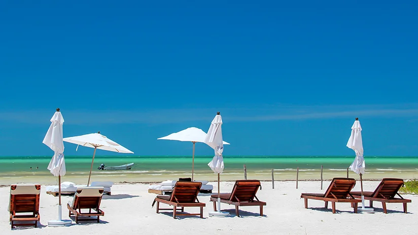 A beach with sun loungers and parasols, ideal for relaxation in the best Holbox hotels.