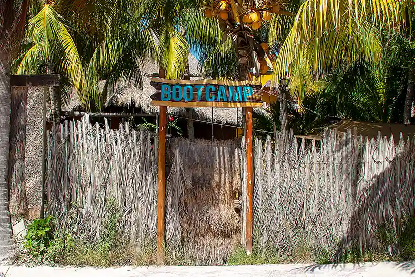 Wooden sign with inscription at the entrance to the Holbox Bootcamp