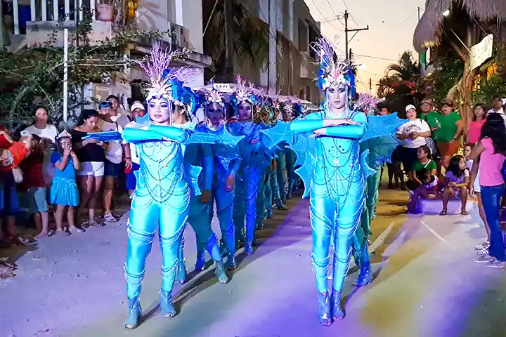 Evening carnival parade on Isla Holbox with a dancing group in the street.
