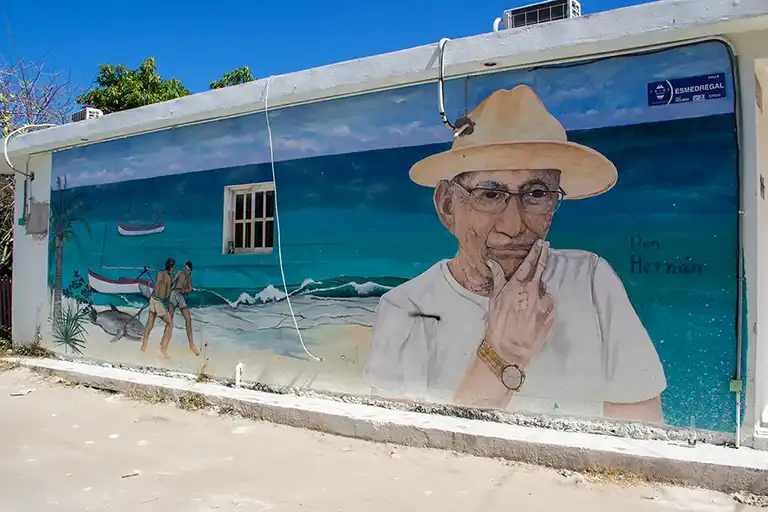 Wandmalerei mit dem Titel „Don Hernán“ über das tägliche Leben der Fischer auf Holbox mit Boot und lokalen Figuren.