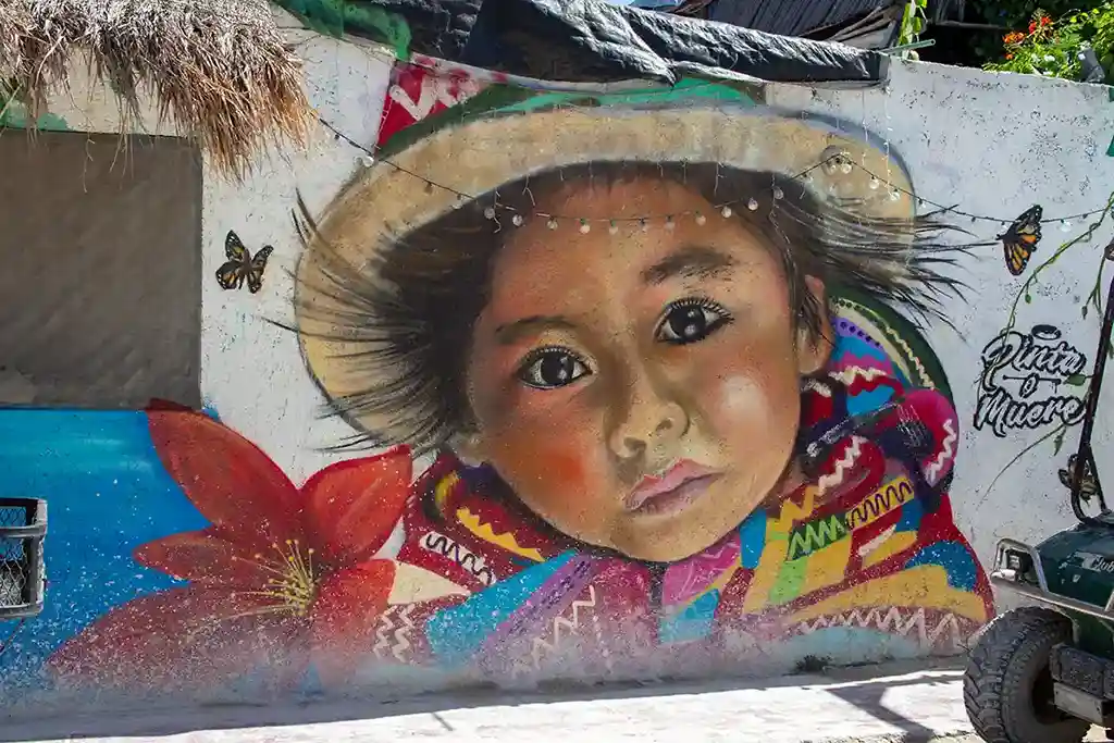 Artistic mural of a child in traditional Latin American clothing surrounded by butterflies.