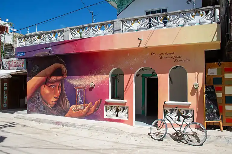 Street-Art-Wandbild eines Mädchens mit einer Sanduhr und einem spanischen Zitat an einer Hausfassade in Holbox, Ausgabe 2023.