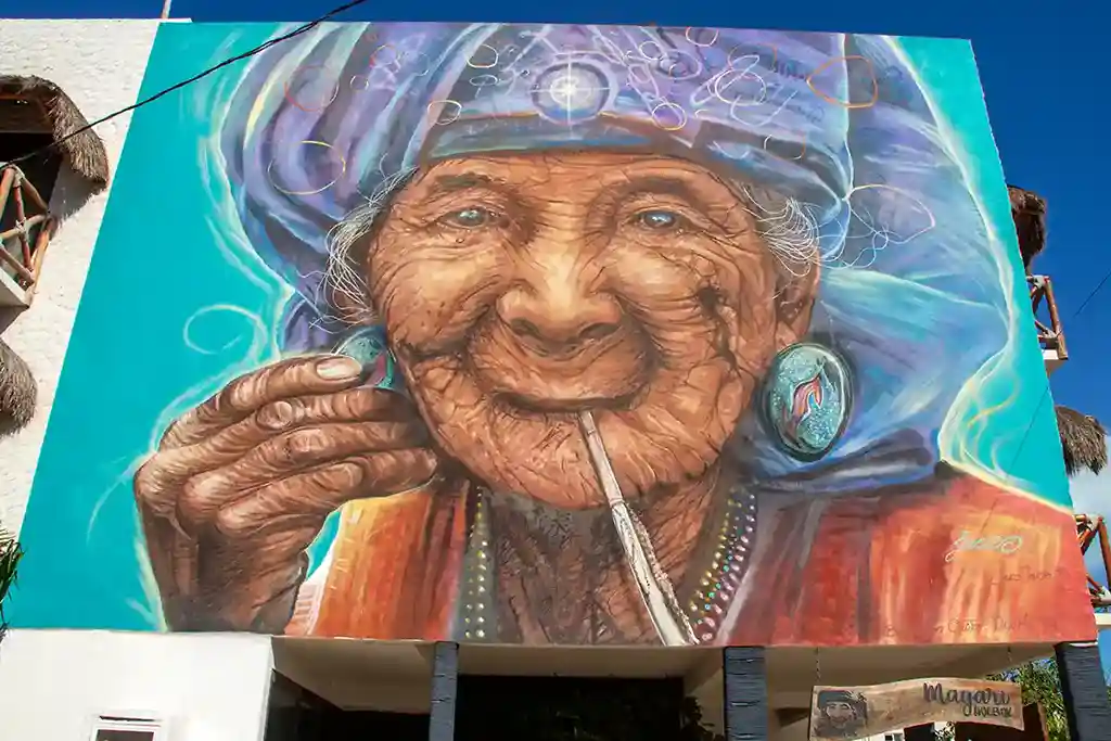 Realistic wall mural of an elderly woman with pearls and a straw at Hotel MAYARI Holbox.