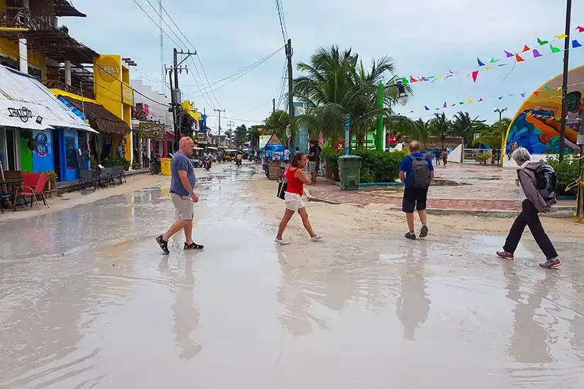Große Wasserpfützen auf den Sandstraßen am Hauptplatz von Isla Holbox nach einem tropischen Regenschauer.