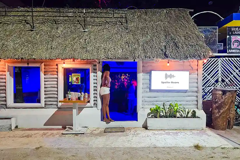 The entrance to the Chinicuil Spoiler Room on Isla Holbox in a white building with a thatched roof.